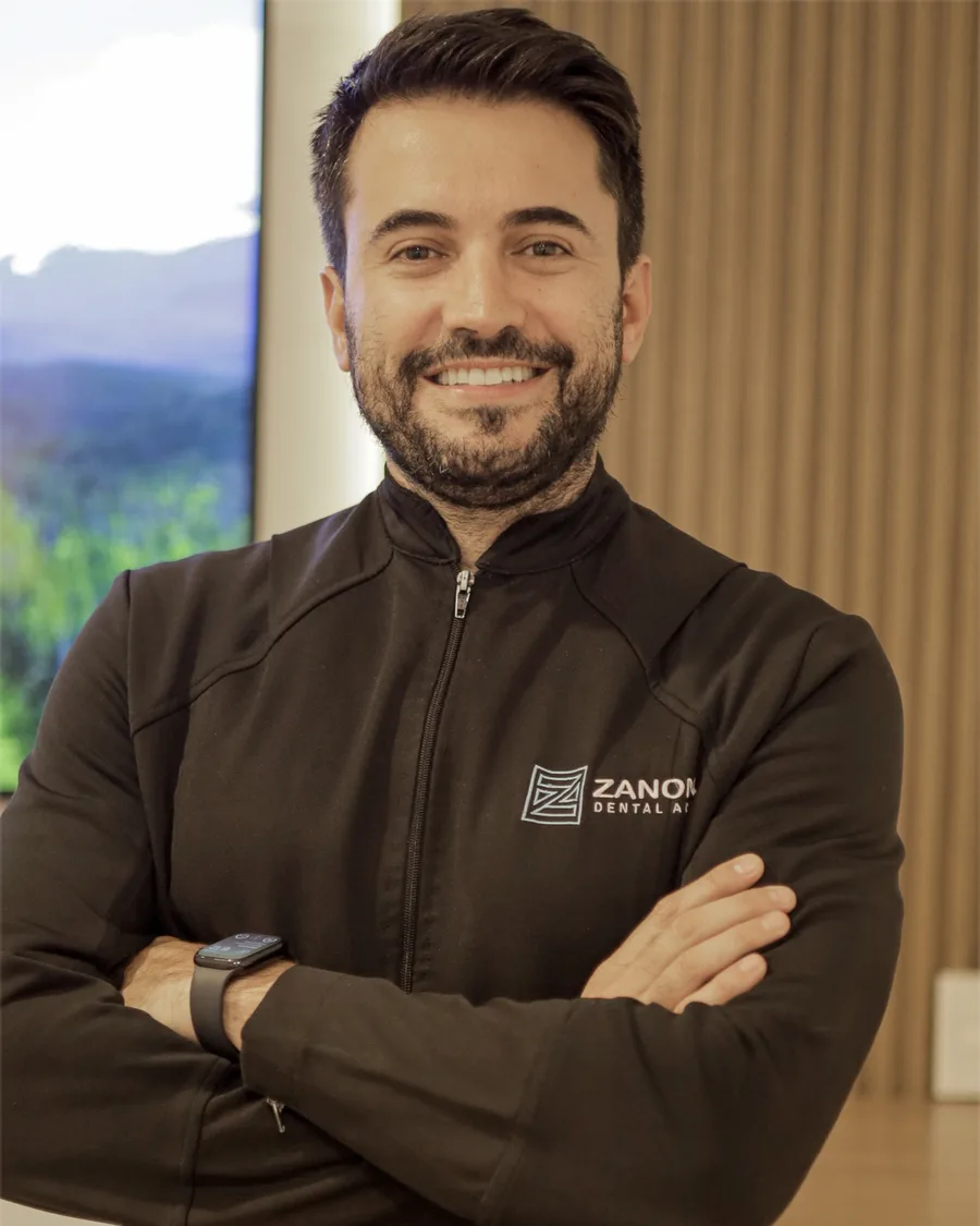 Retrato do Dr. Daniel Zanon sorrindo, de braços cruzados, com jaqueta escura da Zanon Dental.